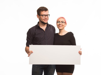 Young happy couple portrait of a confident businessman showing presentation, pointing paper placard gray background. Ideal for banners, registration forms, presentation, landings, presenting concept.