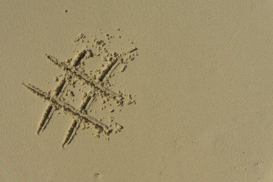 Hashtag symbol drawn into the sand on a beach