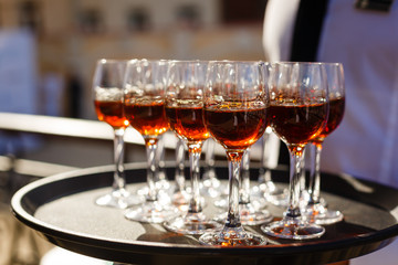 Glasses with red on a tray at the waiter in hand