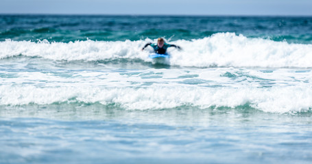 Fototapeta na wymiar Surfer woman with surfboard is paddling on the wave.