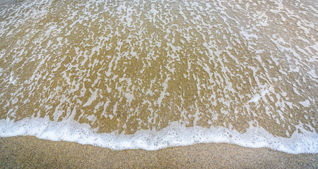 Small ocean sea waves on sandy beach in calm weather.