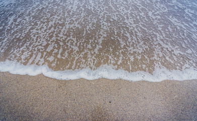 Small ocean sea waves on sandy beach in calm weather.