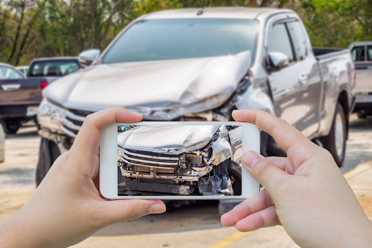 woman using mobile smartphone taking photo of car accident damaged for insurance