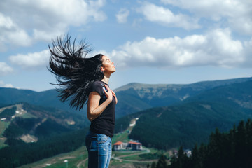 brunette girl on the top of the mountain with streaming hair