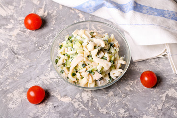 Salad with squid, egg and cucumber in a glass bowl