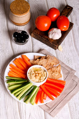 hummus served in a bowl with fresh vegetable sticks and whole grain crackers