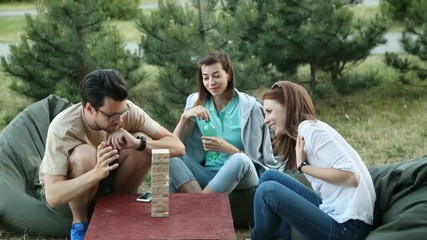 Happy friends play board games in nature. summer holidays. leisure and people concept - group
