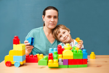 mother and little son  playing with lots of colorful plastic blocks constructor indoor.  The happy family spends time together at home.