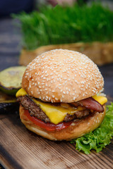 Cheeseburger on the wooden table with grilled vegetables