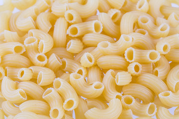Dried pasta or elbow macaroni over white background - closeup