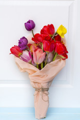 bouquet of colorful tulips wrapped in paper on  a wooden  background 