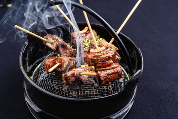 Meat on skewers smoks in a brazier