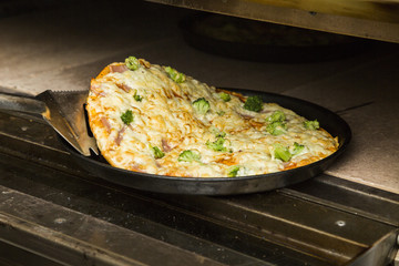 Black metal baking sheet with hot fresh pizza.