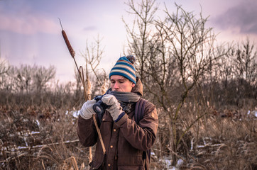 Photographer in mittens in frost makes photos in nature