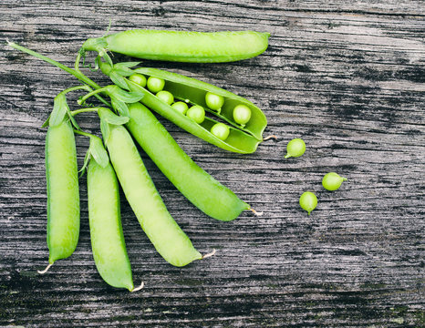 Pods of green peas on a old wooden surface close up, top view