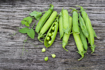 Pods of green peas on a old wooden surface close up, top view