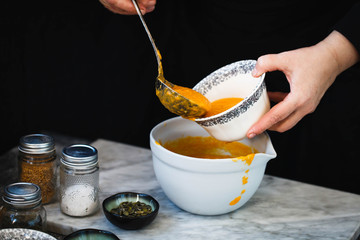 Person pour creaming pumpkin soup in bowl with ladle