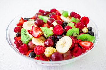 Fresh fruit salad in bowl on white rustic table.