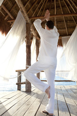 homme qui fait du yoga sur une terrasse sur la mer