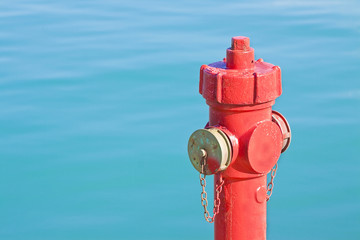 Red fire hydrant against a water background - concept image with copy space