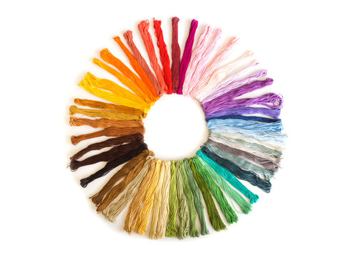 Color cross stitch embroidery on white background. Colorful fabric. Sort by color shade and design in circle shape. Top view.
