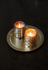 Lighted candles in golden candlesticks on a round gold tray