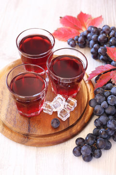 Three glasses of grape juice with ice and black grapes