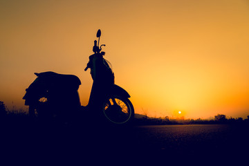 Silhouette scooter standing on field at sunset