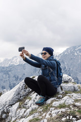 Female hiker making a selfie with her smart phone with hills in  background