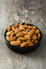 Almonds in black bowl on wooden table

