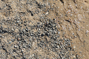 Texture of wet coastal sand with pebbles and shells