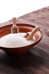 scoop with white sand and lump sugar on brown wooden background