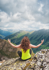 Naklejka premium Woman doing exercise on the top of mountain