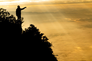 Silhouette of a man on top of mountain. Man point to sky, Success and motivated concept
