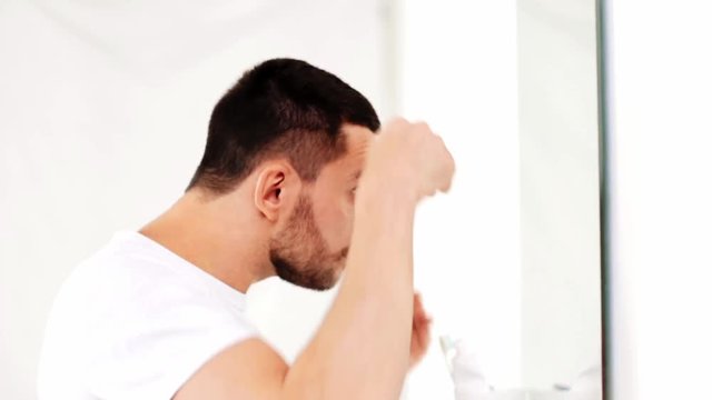happy man applying hair styler at bathroom