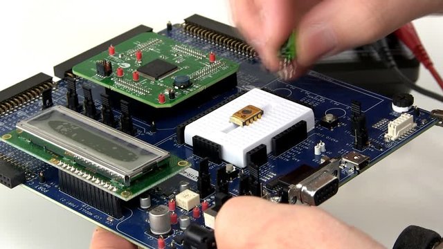 An engineer creates a prototype circuit by installing components in breadboard area of development board