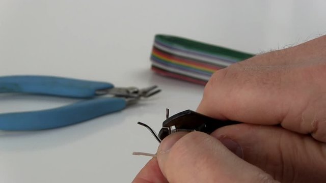 A technician strips insulation from ribbon cable wire in preparation for soldering