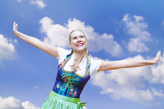 woman in dirndl spreading her arms and smiles