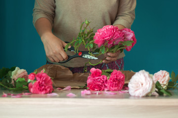 Fototapeta na wymiar girl florist cut the stem beautiful pink roses