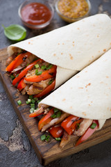 Close-up of wheat wraps with barbecued chicken and fresh vegetables, vertical shot, selective focus
