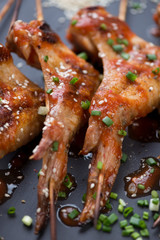Close-up of wooden skewers with grilled chicken wings with sesame, green onion and sauce, selective focus