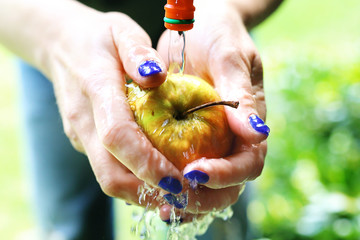 Soczyste ekologiczne jabłko.  Kobieta myje jabłko pod bieżącą wodą. - obrazy, fototapety, plakaty