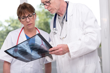 Two doctors examining x-ray report