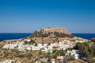 Lindos town at the foot of the mountain. Acropolis of Lindos is located on a hill above the town. Bay and harbor with beach.