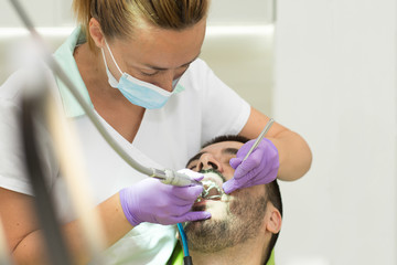 Female dentists examining and working on male patient.Dentist's office.