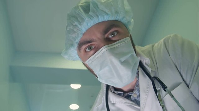 Doctor in mask looking down at patient checking his consciousness