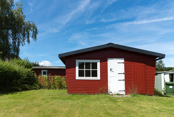 Fototapeta na wymiar Red garden shed with white door on a sunny day