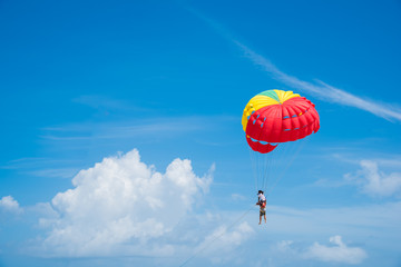 People enjoy parasailing water sport, Flying on a parachute behind a boat on a summer holiday by the sea at Patong beach. The most famous tourist attraction in Phuket province, Thailand.