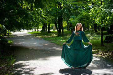 Young, attractive girl in a green dress in a city park.