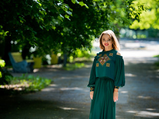 Naklejka premium Young, attractive girl in a green dress in a city park.